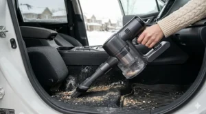 A 2-in-1 vacuum in handheld mode being used to clean debris from a car interior after a typical Canadian winter commute.