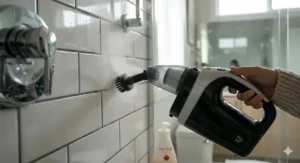Handheld steam cleaner nozzle removing grime from bathroom grout and chrome faucets, a key feature of the 2-in-1 steam mop and handheld system.