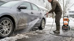 Illustration of a 2000 PSI pressure washer removing winter road salt from a sedan in a snowy Canadian driveway.